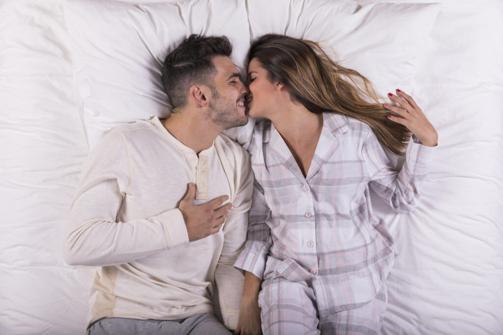 Casal se beijando na cama.